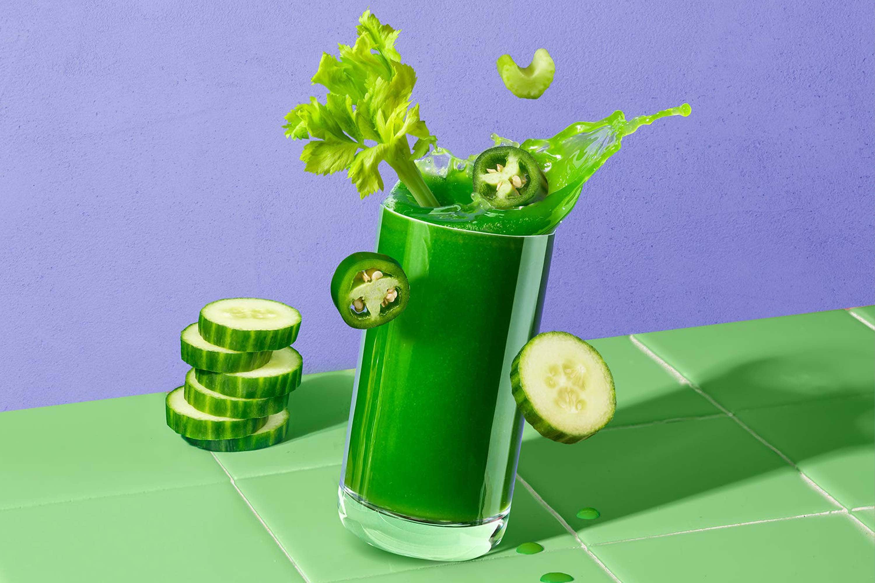 Koktajl z zielonych warzyw na stojący na zielonych płytkach i fioletowym tle
